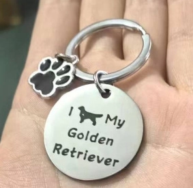 Détail d'un porte-clés Golden Retriever avec pendentif patte noire tenu dans la main