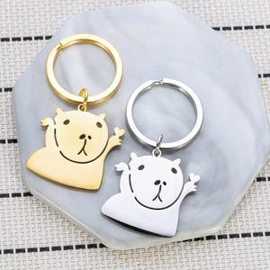 Polished stainless steel capybara keychains in gold and silver on marble tray