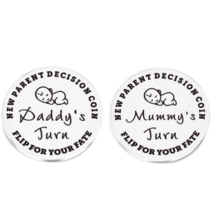 Close-up of stainless steel decision coins with engraved Daddy and Mummy's Turn patterns
