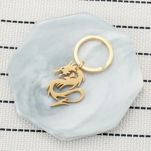 Gold Chinese dragon keychain with minimalist circular ring on a marble display