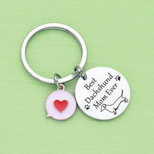 Stainless steel Dachshund Mom keychain with pink heart charm on green background
