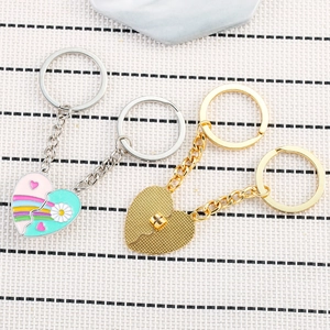 Detail of magnetic heart keychains with rainbow and daisy enamel patterns on white background