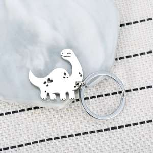 Polished stainless steel dinosaur keychain with heart cutout on a marble tray