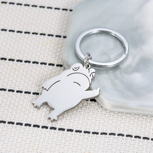 Funny cartoon frog stainless steel keychain with humorous gesture on marble surface