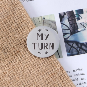 Polished stainless steel decision coin with My Turn engraving on rustic burlap
