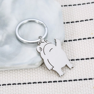 Funny cartoon frog stainless steel keychain with middle finger gesture on marble background