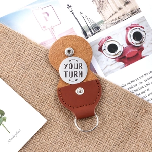 Brown leather key chain with stainless steel coin engraved with Your Turn and arrow