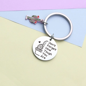Macro shot of stainless steel keychain with cactus charm and inspirational engraving