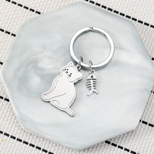 Cute stainless steel cat and fish bone keychain set on a marble tray background