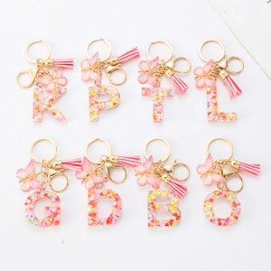 Pink resin alphabet keychains with glitter, butterfly charm, and decorative tassels
