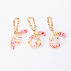 Detail of resin letter charms with colorful heart sequins and pink leather tassels