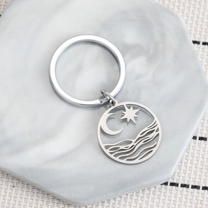 Stainless steel keychain with moon stars and wave pendant on marble surface