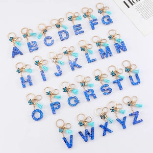 Blue glitter resin alphabet keychain set with tassels and butterfly charms on white background