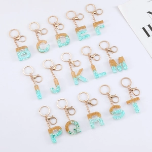 Handmade resin alphabet keychain with gold foil and green stones in a matrix layout