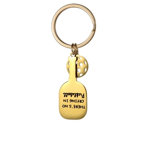 Detail of golden pickleball racket keychain showing engraved text and mini ball charm