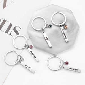 Custom stainless steel birthstone keychains with engraved months on a marble tray