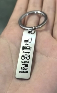Macro shot of polished stainless steel keychain with Eat Sleep Game Repeat engraving