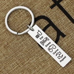 Polished stainless steel keychain with Eat Sleep Game Repeat icons on rustic burlap