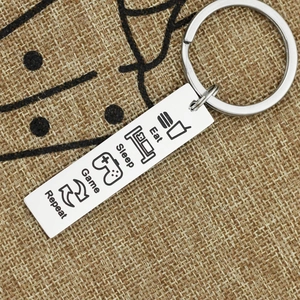 Stainless steel keychain with Eat Sleep Game Repeat icons on rustic burlap background