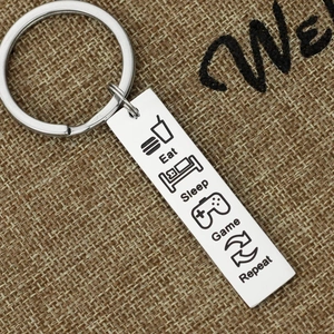 Stainless steel keychain with Eat Sleep Game Repeat text on rustic jute background