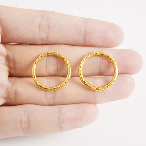 Polished 18k gold plated stainless steel hammered circular rings held by hand