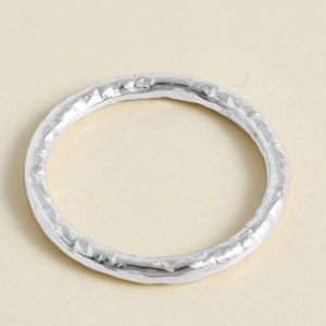 Macro detail of silver stainless steel ring with hammered irregular lava texture