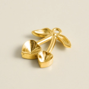 Macro view of gold 304 stainless steel cherry charm with heart-shaped grooves and leaves