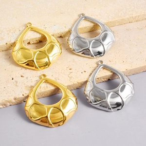 Détail de pendentifs gouttes martelés en or et argent sur pierre de travertin