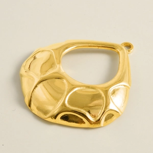 Détail de la texture martelée irrégulière sur le pendentif goutte doré et creux