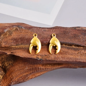 Detalle de colgantes de pinzas de cangrejo en acero chapado en oro 18k sobre madera