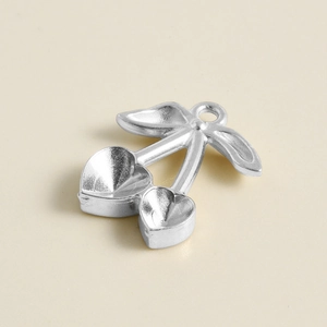 Macro detail of cherry-shaped stainless steel pendant with heart-shaped stone settings