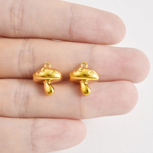 Hand holding two golden 304 stainless steel mushroom charms for DIY jewelry necklaces