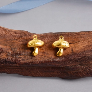 Macro view of two golden mushroom pendants in polished stainless steel for DIY jewelry