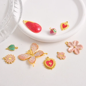Detalle de dijes de esmalte rosa y rojo con base dorada en forma de corazón y flor