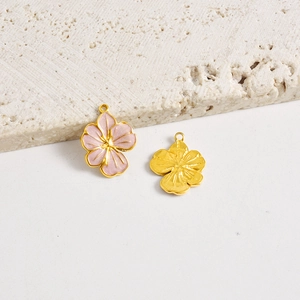 Vista detallada de los dijes de flores en esmalte rosa y colgantes dorados para joyería DIY
