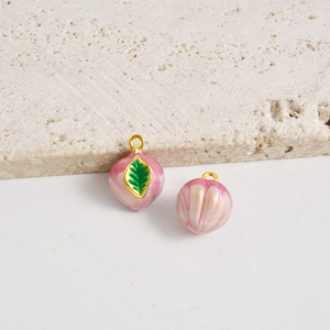 Detalle macro de colgantes de melocotón esmaltado con veteado rosa y ganchos dorados para joyas
