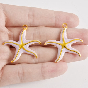 Makroaufnahme von zwei lila Emaille-Seestern-Anhängern mit 18k Vergoldung für DIY-Schmuck
