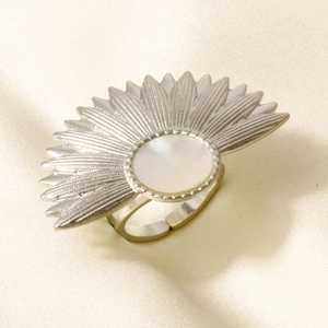 Detail of fan-shaped stainless steel ring with white shell inlay on beige silk cloth