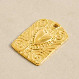 Detail of 18k gold heart pendant with vintage relief patterns and engraved textures