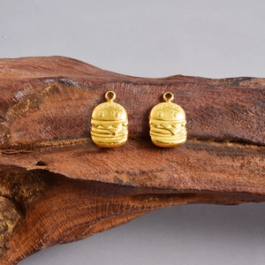 Detailed close-up of 18K gold plated hamburger charms on rustic wood texture