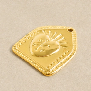 Macro shot of 18k gold plated heart pendant with sunburst engraving for jewelry making