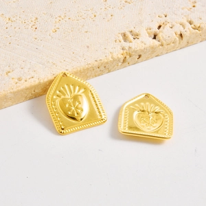 Polished 18k gold heart pendants with embossed star motifs on a stone display base