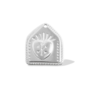 Detailed view of silver house-shaped pendant with embossed heart and snowflake patterns