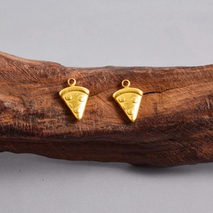 Macro detail of two 18K gold plated pizza slice charms on a textured wooden stand