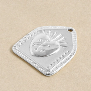 Macro shot of silver heart relief charm with snowflake engraving and hanging hole