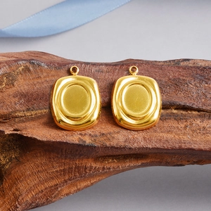Macro view of gold oval pendant charms with a smooth center and vintage style
