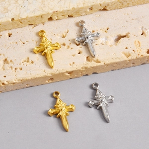 Détail de pendentifs croix épée gothiques en finitions or et argent sur pierre