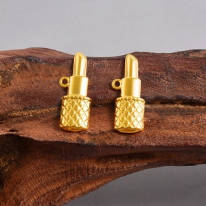 Détail de pendentifs rouges à lèvres dorés avec motifs losanges sur bois
