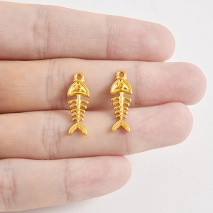 Pendentifs arêtes de poisson dorés pour bijoux DIY, présentés sur main pour la taille