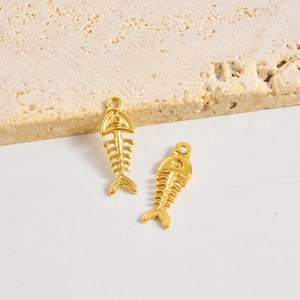 Pendentifs arêtes de poisson dorés pour bijoux DIY présentés sur un socle en marbre